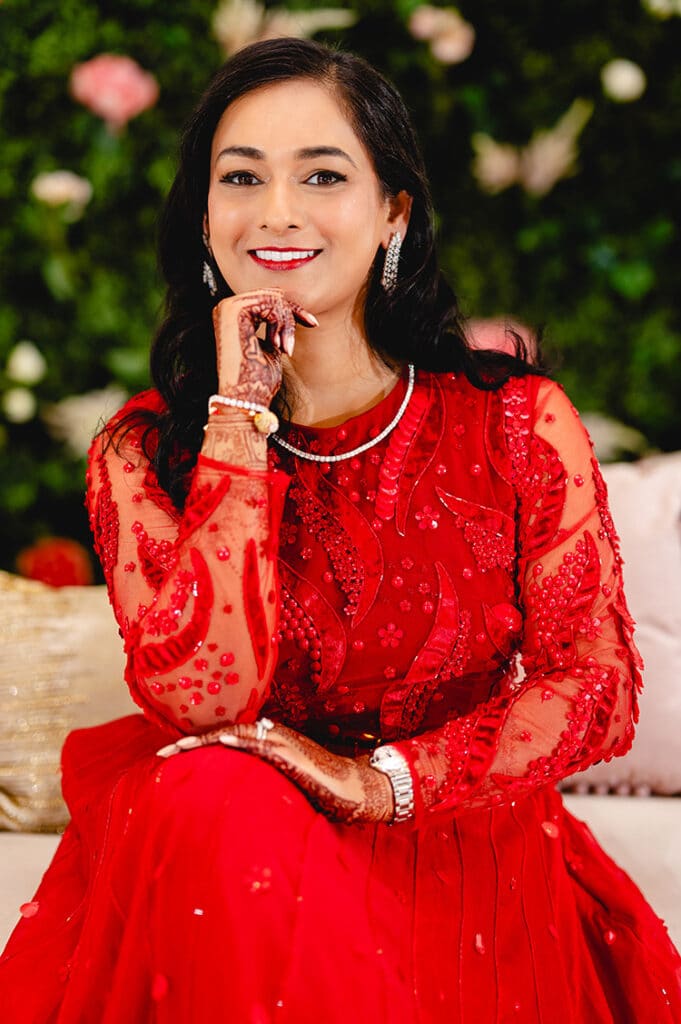 Indian bride wearing a traditional red dress and makeup that compliments her skin tone and dress, on her wedding day at the Old Post Office Chicago